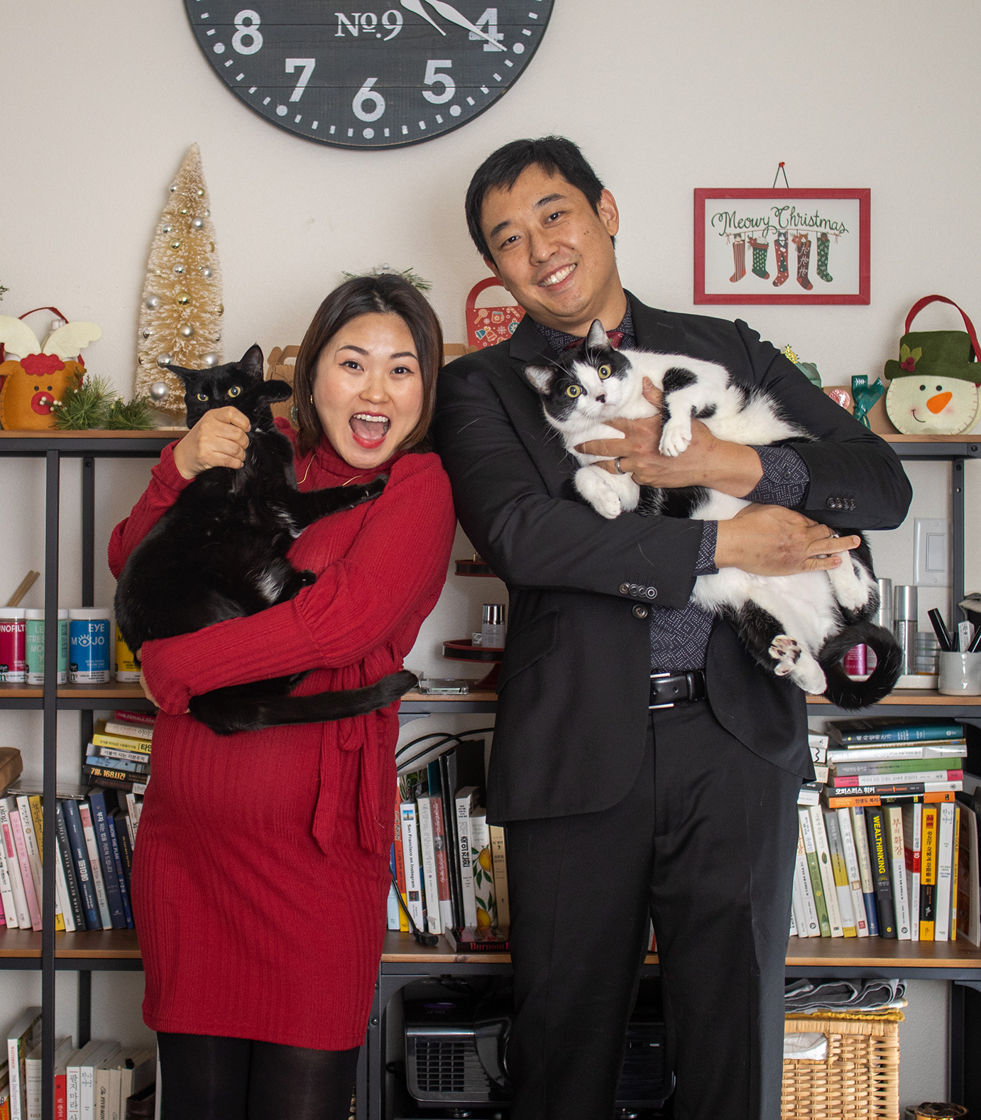 A portrait of Jim Park, his wife, and their two cats. The cats are not wearing leashes, but given the uncomfortable expression on their faces, they probably should be.